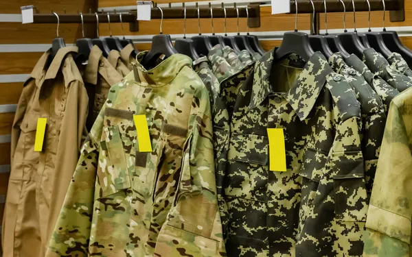 Photo of tactical military shirts hanging on store racks with sale and price tags.