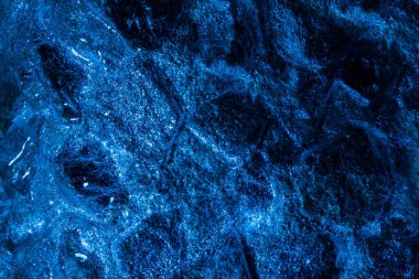 Koyu mavi tonlu, buz yüzeyi dokusuyla kaplı donmuş ahşap kömürün fotoğrafı..
