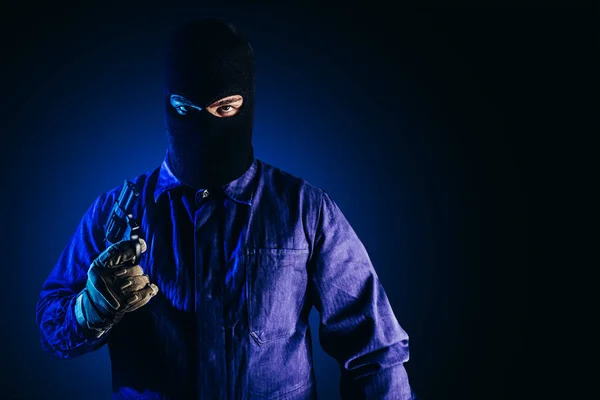 Foto Ladrón Máscara Overoles Guantes Pistola Pie Sobre Fondo Azul —  Fotos de Stock