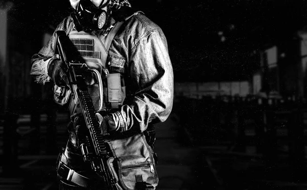戦術的な軍装の都市兵士の黒と白の写真と暗い工場の背景にライフルとガスマスクと立ってガスマスク — ストック写真