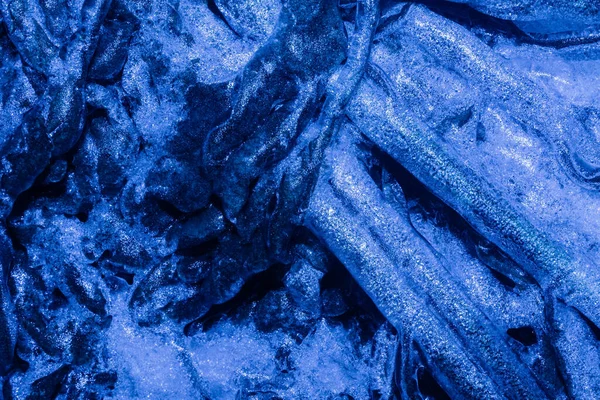 蓝色调的冻叶和覆盖在冰背景纹理上的枝条的照片 — 图库照片