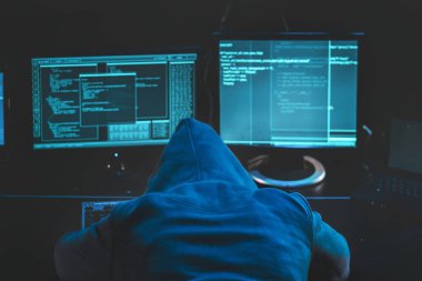 Çok çalışan yorgun hacker. Bilgisayarında uyuyan kapüşonlu bir hacker, ekrandaki kötü niyetli kod yazılımı veri merkezini hackliyor. Resim indir