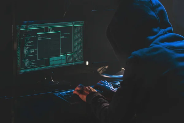 Monitörlerdeki siber suçlu hackleme sistemi, bilgisayar korsanlarının elleri. İnternet suçu konsepti. Hacker şifreli saldırı kurbanı bilgisayarını çalıyor ve karanlıkta şifre üzerinde çalışıyor. Hackleme ve kötü amaçlı yazılım konsepti. Siber Suçlar