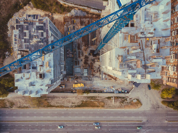Contstruction Site from above. Aerial view of new apartment under construction. Top view of building at the road. Under construction site, crane, and car traffic transportation. Download high quality