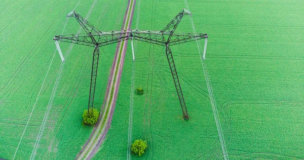 Top Elektrische hoogspanningspost, Hoogspanning energie transmissie. Spanning post.High-voltage toren in groen veld achtergrond. Energiedistributie. — Stockfoto