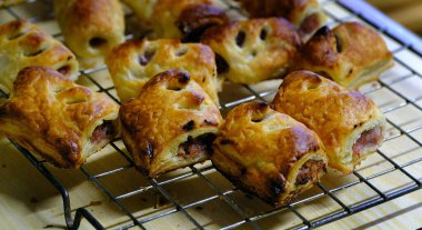 Ev mutfağındaki soğutma tepsisinde taze pişmiş küçük sosisli börekler..