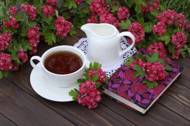 Kahverengi ahşap arka planda pembe çiçekli bir fincan çay.