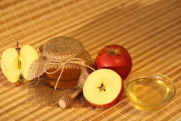 Red fresh apples with honey on wooden background