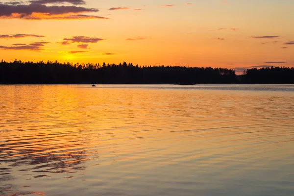 Одинокая лодка на озере во время заката — стоковое фото
