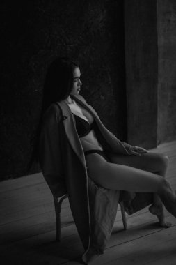 İç çamaşırı ve ceket giymiş çekici genç bir kadının siyah beyaz portresi. Retro yumuşak tahıl fotoğraf efekti