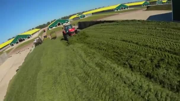 Летающий вокруг трактора вертолет в бункере на ферме — стоковое видео