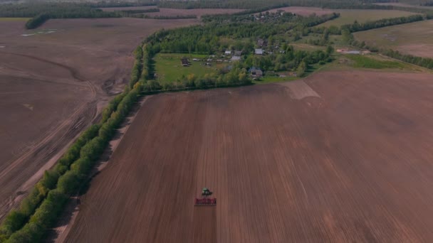 Dron śledzi ciągnik pracujący w terenie. — Wideo stockowe