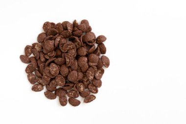 Beyaz arka planda izole edilmiş çikolata taneleri, sağlıklı kuru kahvaltı konsepti, mısır gevreği yığını, üst manzara.