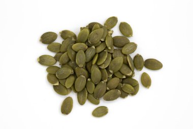 Beyaz arka planda izole edilmiş bir yığın yeşil kabak çekirdeği, soyulmuş tohumlar, üst manzara.