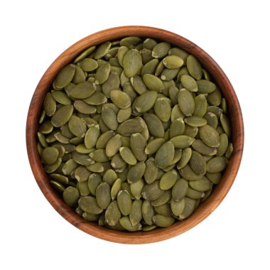 Beyaz zemin üzerinde izole edilmiş ahşap kasede yeşil kabak tohumları, çiğ çekirdekler, üst görünüm