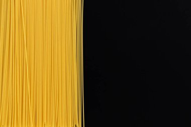 Yazı için fotokopi alanı olan pişmemiş İtalyan spagettisi çerçevesi, yakın plan, siyah arkaplanda sarı ham makarna dokusu.