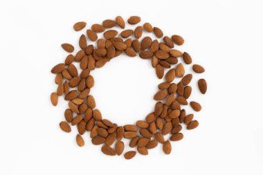 Beyaz arkaplanda izole edilmiş metin için kopyalama alanı olan soyulmuş badem fıstıklarından oluşan bir çerçeve. Sağlıklı atıştırmalıklar.