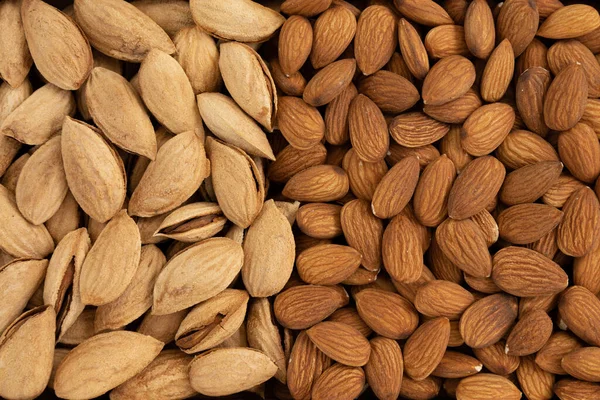 Kabuğu soyulmuş ve soyulmamış badem yığını yakın plan ve doku, vejetaryenler için sebze proteini, düz yatak.