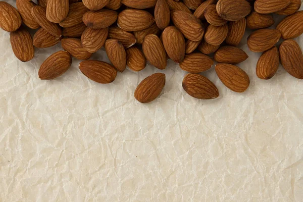 frame of peeled almond nuts with copy space for text isolated on parchment for baking, healthy snacks, close up