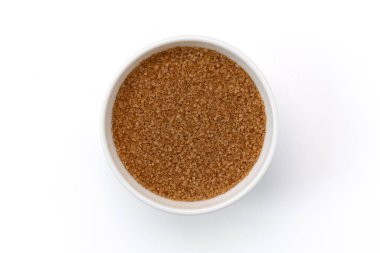 Beyaz arka planda izole edilmiş seramik kasede rafine edilmemiş doğal kahverengi şeker, yakın plan kamış şekeri manzarası