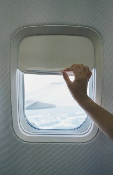 person closing airplane window