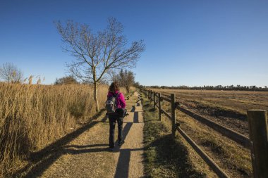 Young girl walking and photographing birds in Aiguamolls De L Emporda Nature Park, Spain.