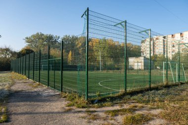 Etrafı yüksek çitlerle çevrili küçük bir okul stadyumu. Çitin arkasındaki High Shcool Futbol Stadyumu. Renkli bir sabah.