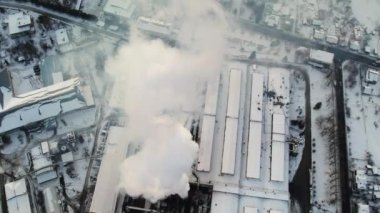 Güneşli kış gününde dumanı tüten odun fabrikasının hava görüntüleri.