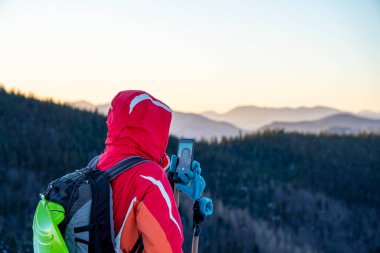 Güneşli bir akşamda karla kaplı güzel dağda selfie çeken bir kadının manzarası.