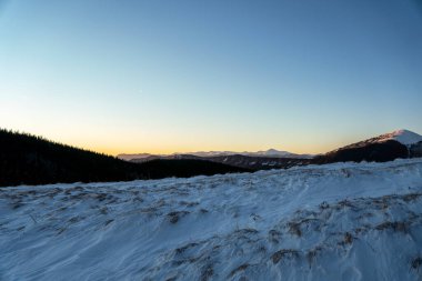 Güneşli bir akşamda güzel karla kaplı dağın manzaralı görüntüsü.