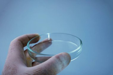 Mavi arka planda laboratuvar ekipmanlarını tutan bilim adamının yakın plan fotoğrafı.