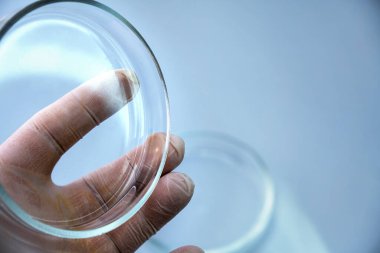 Mavi arka planda laboratuvar ekipmanlarını tutan bilim adamının yakın plan fotoğrafı.