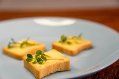 Kahvaltı için sandviç hazırla. Mavi tabakta mikro yeşillikli sandviçler ahşap arka planda lezzetli ve taze organik gıdalar sağlıklı kahvaltı konsepti