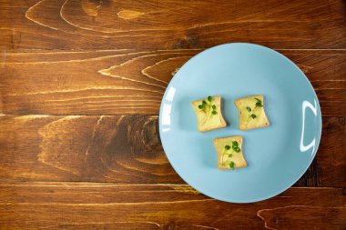 Kahvaltı için sandviç hazırla. Mavi tabakta mikro yeşillikli sandviçler ahşap arka planda lezzetli ve taze organik gıdalar sağlıklı kahvaltı konsepti