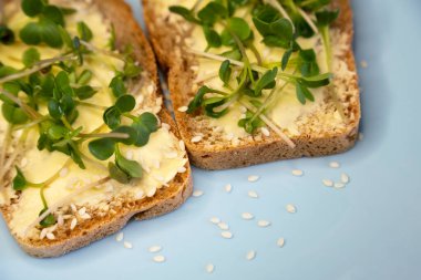 Kahvaltı için sandviç hazırla. Mavi tabakta mikro yeşillikli sandviçler ahşap arka planda lezzetli ve taze organik gıdalar sağlıklı kahvaltı konsepti