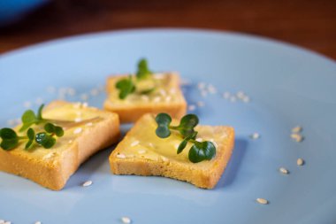 Kahvaltı için sandviç hazırla. Mavi tabakta mikro yeşillikli sandviçler ahşap arka planda lezzetli ve taze organik gıdalar sağlıklı kahvaltı konsepti