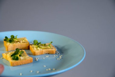 Kahvaltı için sandviç hazırla. Mavi tabakta mikro yeşillikli sandviçler ahşap arka planda lezzetli ve taze organik gıdalar sağlıklı kahvaltı konsepti