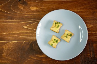 Kahvaltı için sandviç hazırla. Mavi tabakta mikro yeşillikli sandviçler ahşap arka planda lezzetli ve taze organik gıdalar sağlıklı kahvaltı konsepti