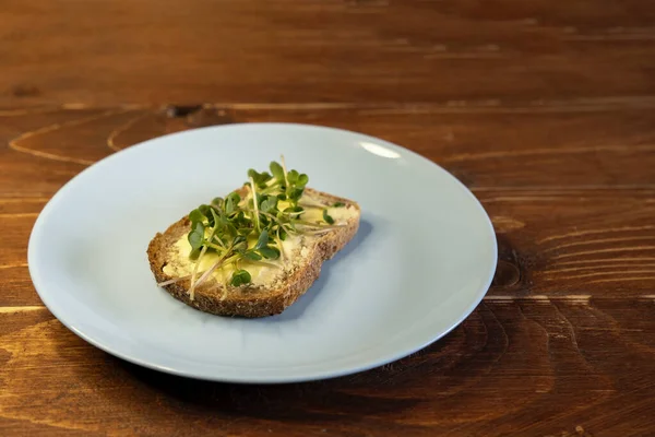 Kahvaltı için sandviç hazırla. Mavi tabakta mikro yeşillikli sandviçler ahşap arka planda lezzetli ve taze organik gıdalar sağlıklı kahvaltı konsepti