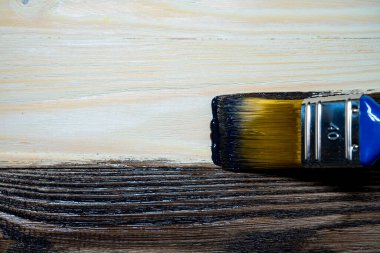 Copy space with paint brush on can lying on wooden background. Close-up paintbrush with liquid dark brown paint on the brush. Painting tools on wooden surface. Top view. Copyspace. Vintage style.