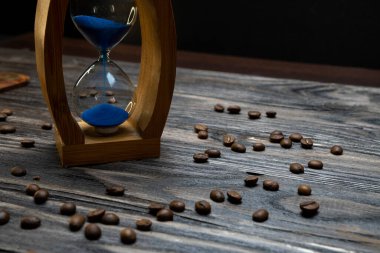 Kum saati ve ahşap bir arka planda kavrulmuş kahve taneleri. Kum saati, kum saati ya da ahşap üzerinde yumurta saati. Antika tarzı ahşap arkaplan.