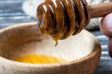 Bal-dipper 'dan damlayan aromatik bal. Kasedeki bal. Ahşap arka planda tahta kaplamalardan bal damlıyor. Seçici odak.