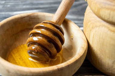 Bal-dipper 'dan damlayan aromatik bal. Kasedeki bal. Ahşap arka planda tahta kaplamalardan bal damlıyor. Seçici odak.