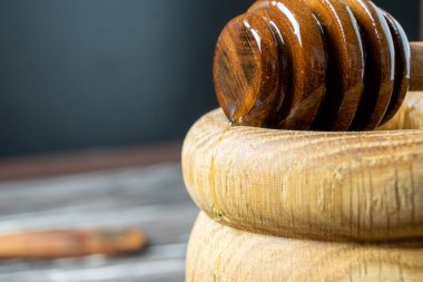 Bal-dipper 'dan damlayan aromatik bal. Kasedeki bal. Ahşap arka planda tahta kaplamalardan bal damlıyor. Seçici odak.