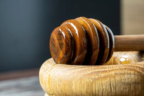 Bal-dipper 'dan damlayan aromatik bal. Kasedeki bal. Ahşap arka planda tahta kaplamalardan bal damlıyor. Seçici odak.