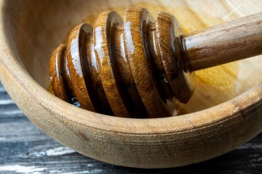 Bal-dipper 'dan damlayan aromatik bal. Kasedeki bal. Ahşap arka planda tahta kaplamalardan bal damlıyor. Seçici odak.