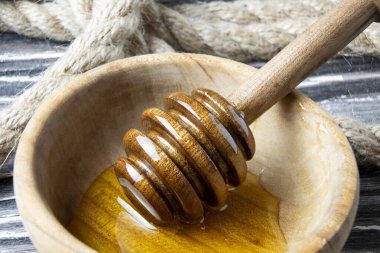 Bal-dipper 'dan damlayan aromatik bal. Kasedeki bal. Ahşap arka planda tahta kaplamalardan bal damlıyor. Seçici odak.