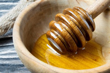 Bal-dipper 'dan damlayan aromatik bal. Kasedeki bal. Ahşap arka planda tahta kaplamalardan bal damlıyor. Seçici odak.