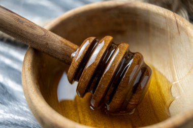 Bal-dipper 'dan damlayan aromatik bal. Kasedeki bal. Ahşap arka planda tahta kaplamalardan bal damlıyor. Seçici odak.