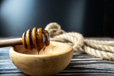 Bal-dipper 'dan damlayan aromatik bal. Kasedeki bal. Ahşap arka planda tahta kaplamalardan bal damlıyor. Seçici odak.